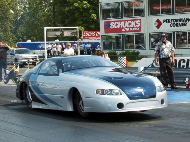 A race car is on a track in front of a chuck 's auto supply sign