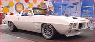 A white convertible car is parked in front of a colorful wall.