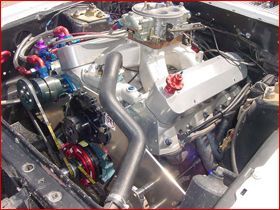 A close up of a car engine with a carburetor