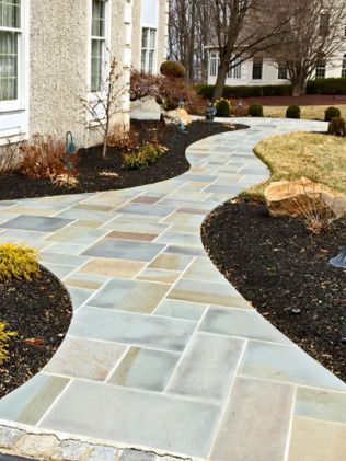 A stone walkway leading to a house in a garden