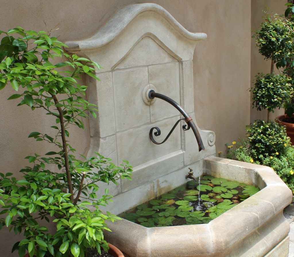 A bird bath sits on a brick patio next to a bench