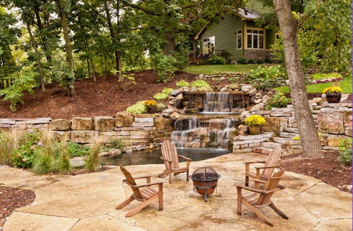 A stone wall surrounds a set of stairs leading up to a house.