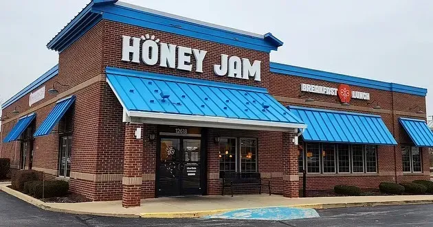 Exterior of Honey Jam restaurant, brick building, blue awnings and signage, overcast sky.
