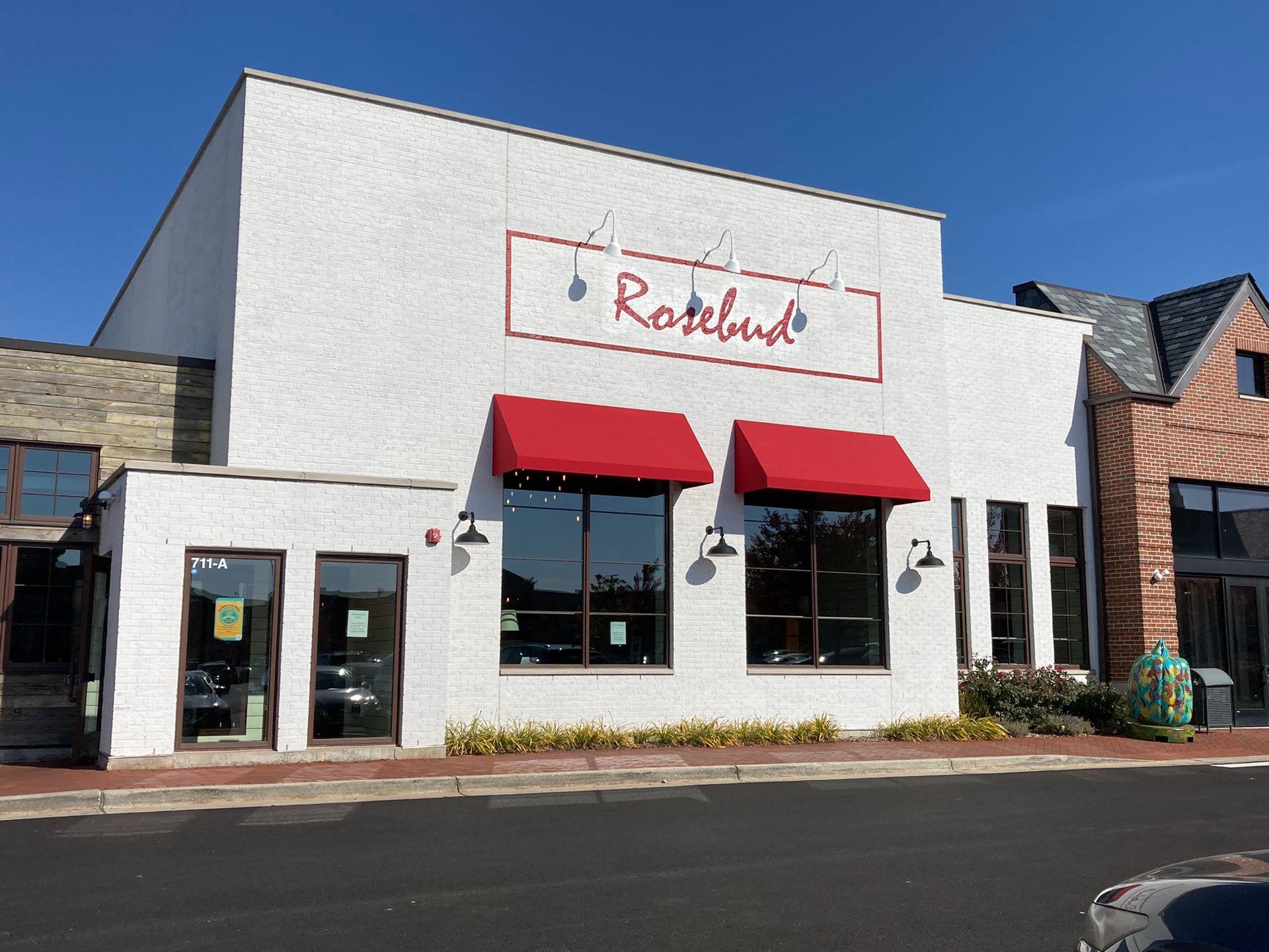 White building with red awning, storefront "Roselund" sign.