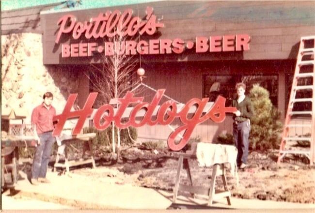 Portillo's restaurant sign installation. Two men stand by newly hung 