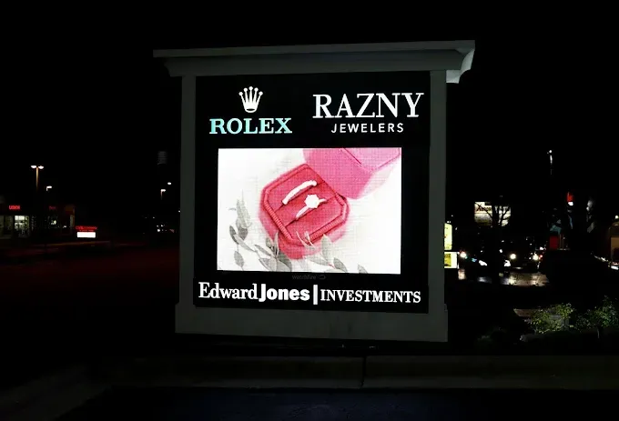 Sign for Razny Jewelers with Rolex logo, a ring in a pink box, and Edward Jones Investments.