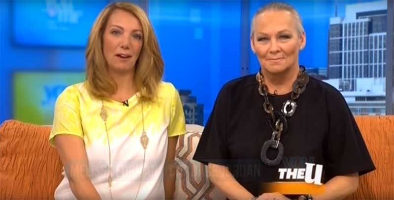 Two women on The View set: one blonde in yellow, one bald in black, smiling.