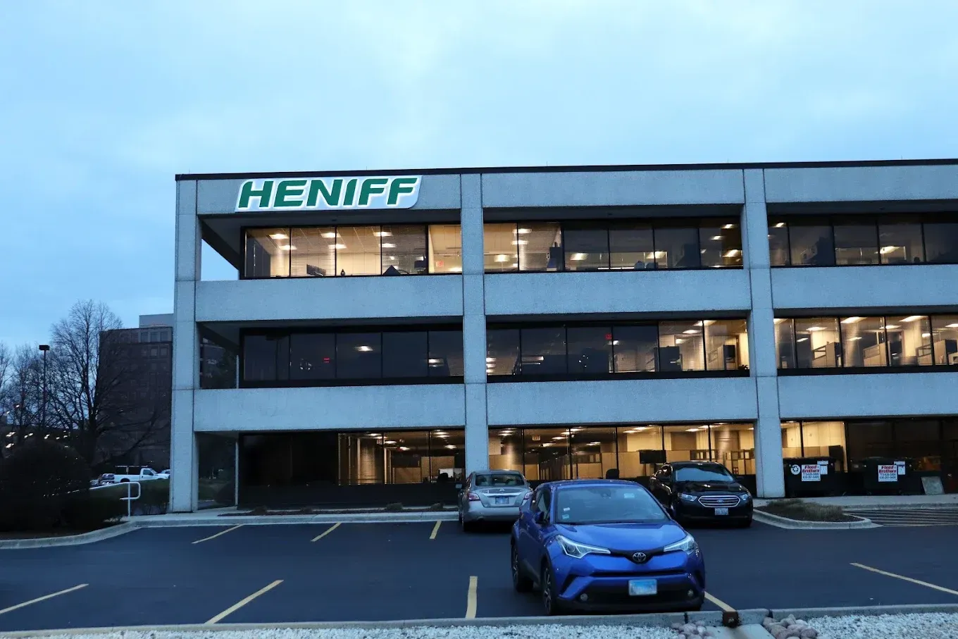 Gray office building with "HENIFF" sign, cars parked in front.