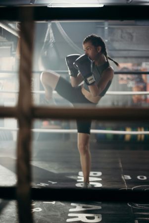 A woman is kickboxing in a boxing ring.
