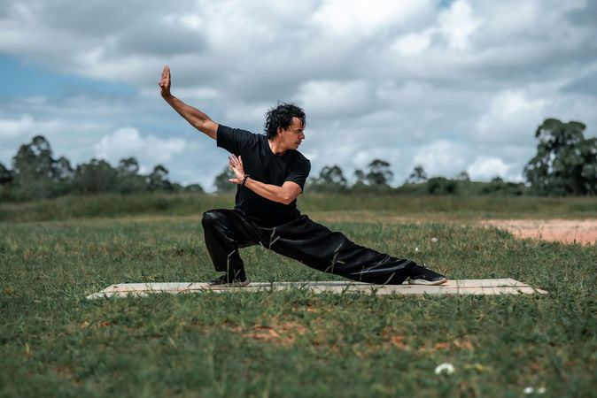 A man is practicing martial arts in a field.
