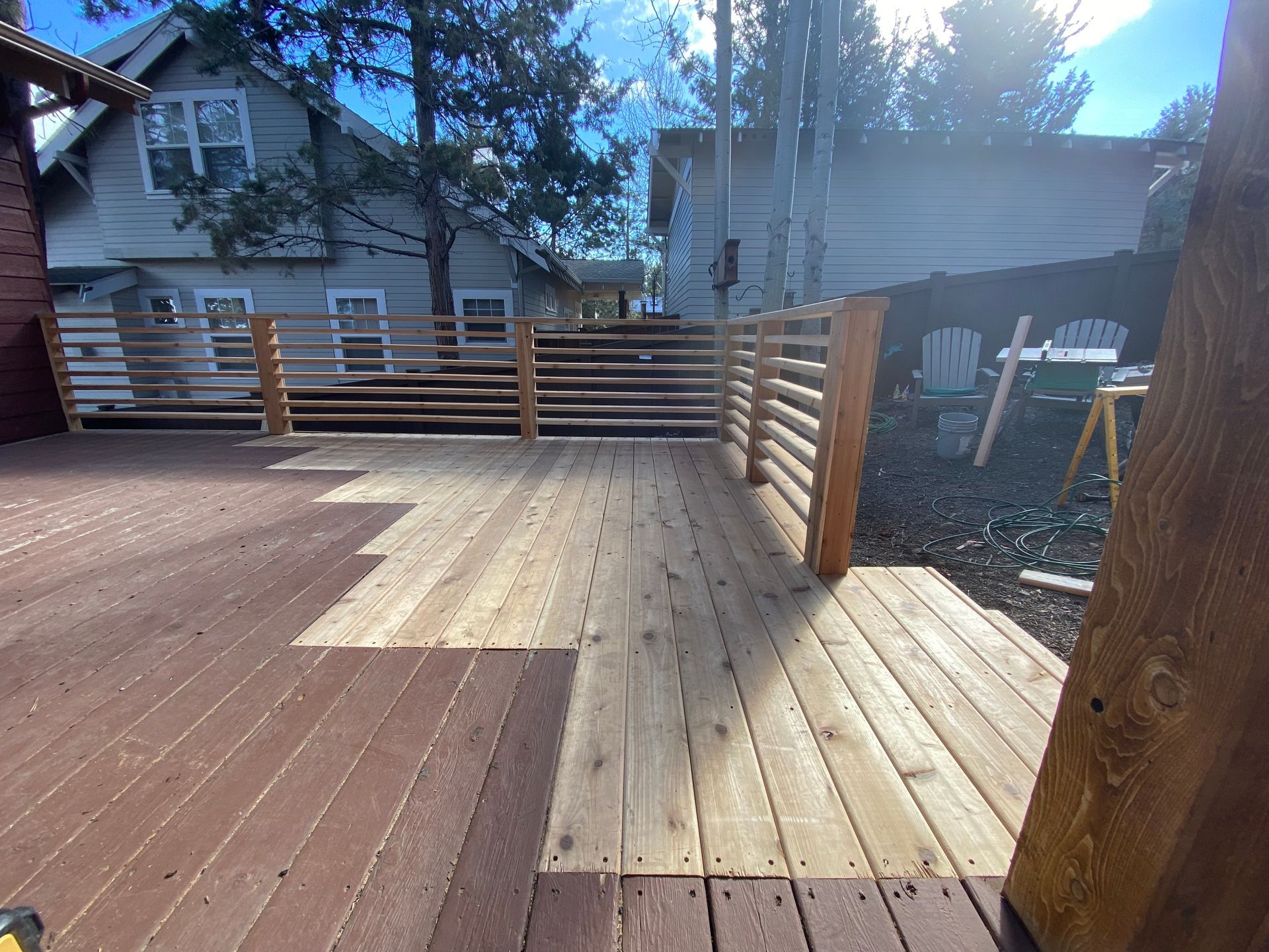 A wooden deck with a railing is being built in front of a house.