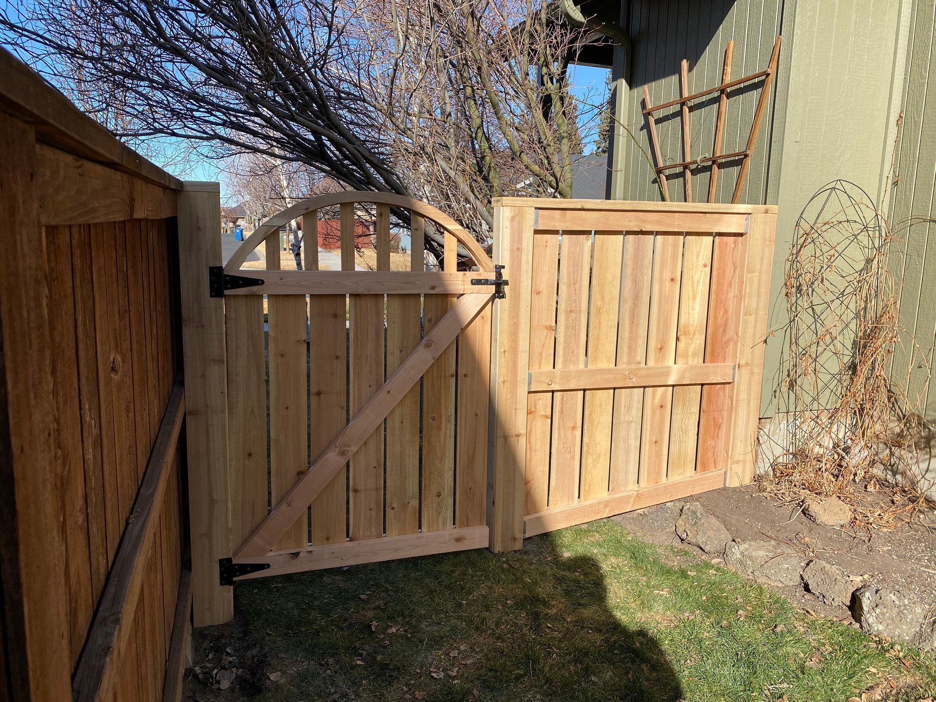 A wooden gate is sitting next to a wooden fence.