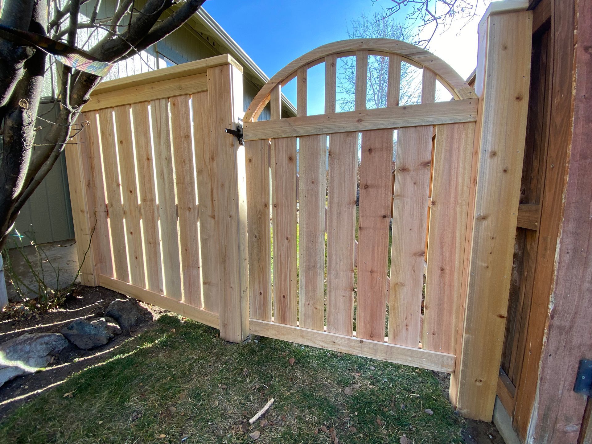 A wooden fence with a gate in the backyard of a house.