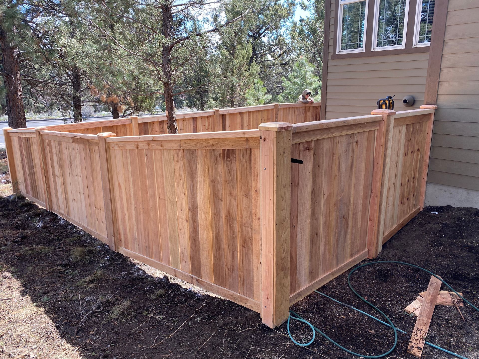 A wooden fence is sitting in the dirt in front of a house.