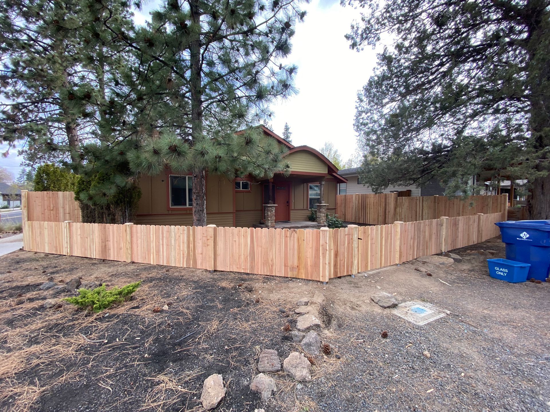 A wooden fence is in front of a house.