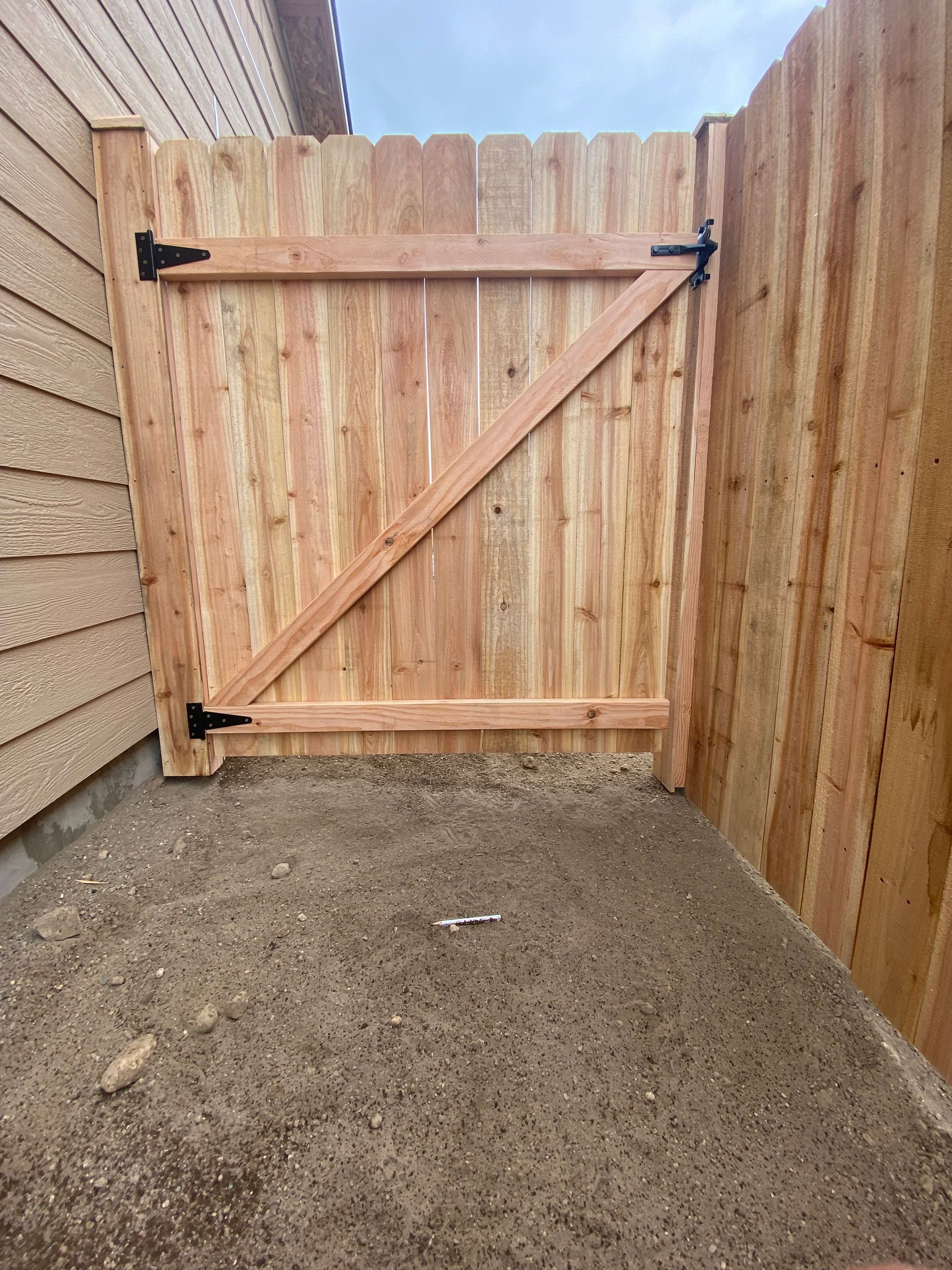 A wooden fence with a gate in the backyard of a house.