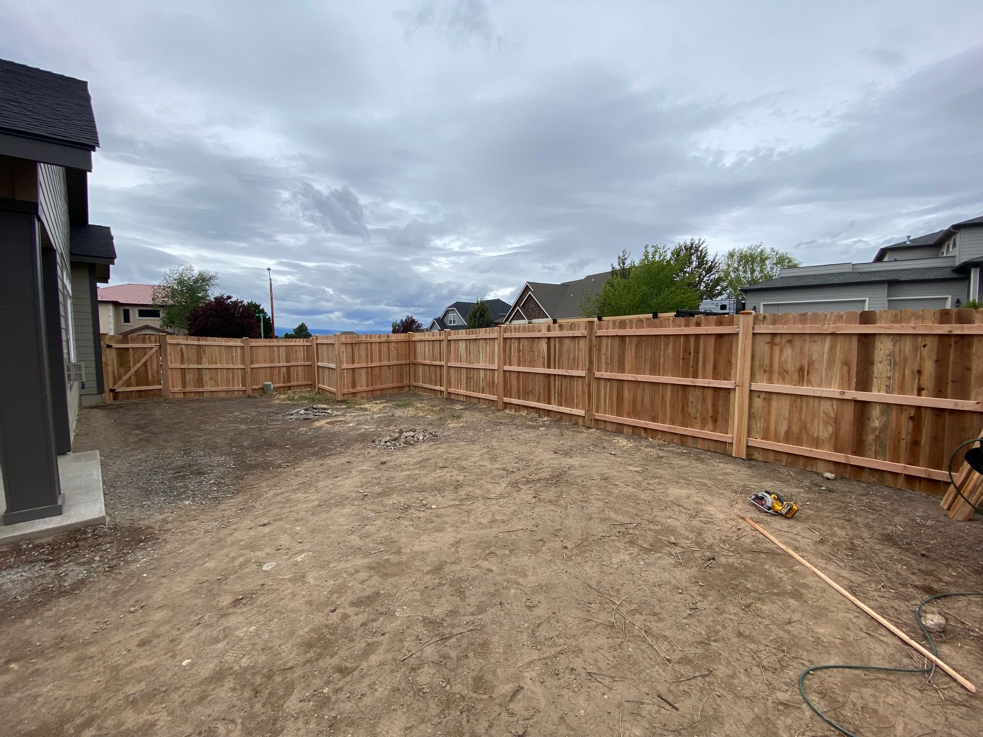 A wooden fence is being built in the backyard of a house.
