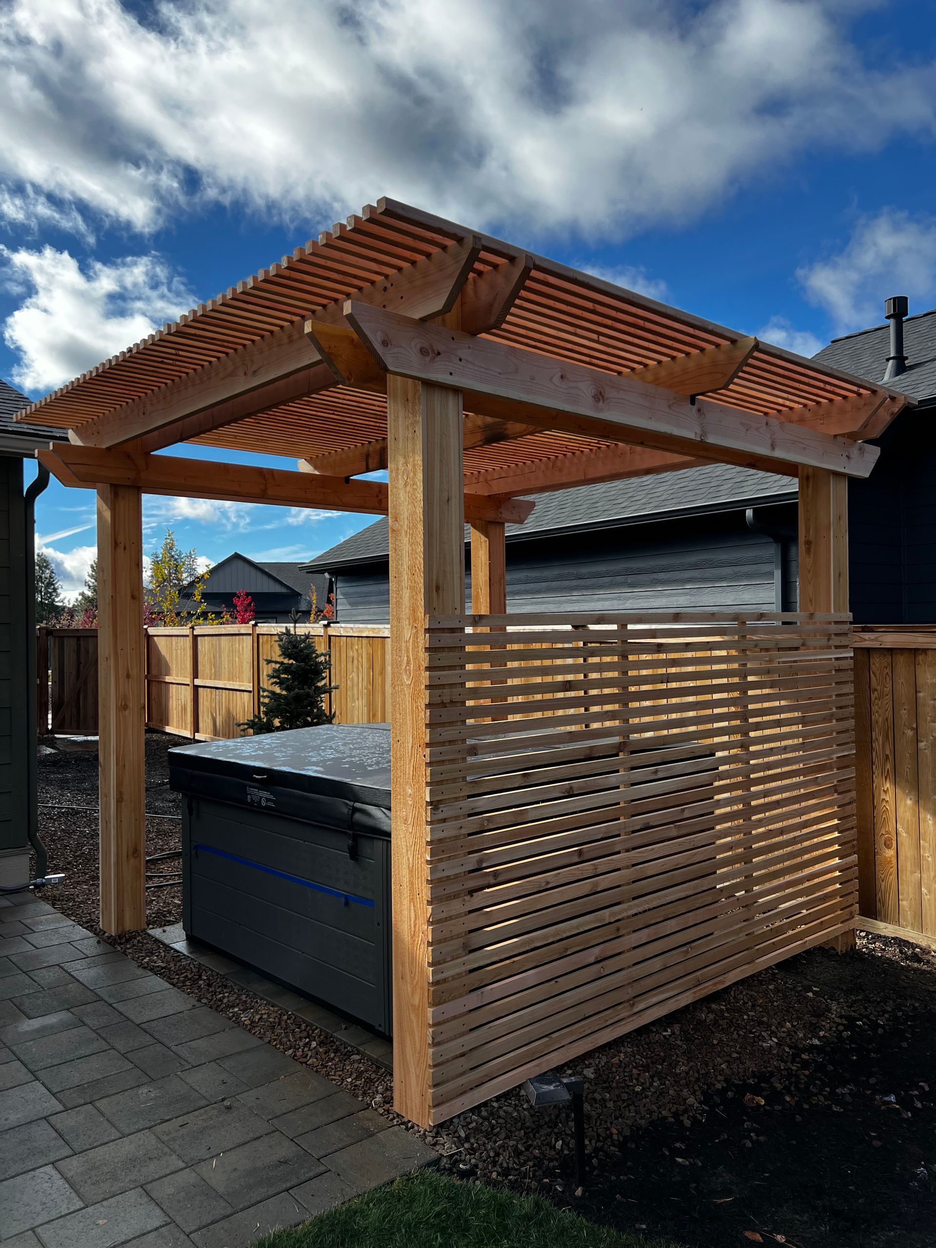 A wooden pergola is sitting next to a hot tub in a backyard.