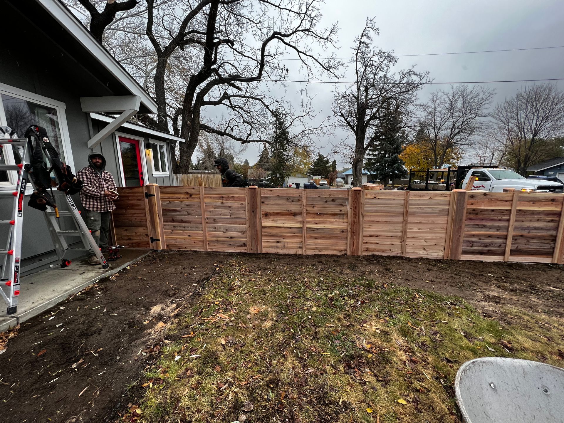 A wooden fence is being built in the backyard of a house.