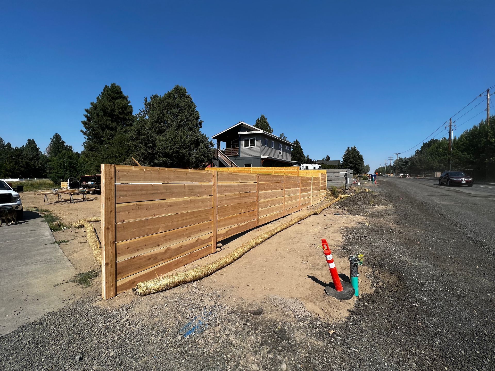 A wooden fence is sitting on the side of a road next to a house.