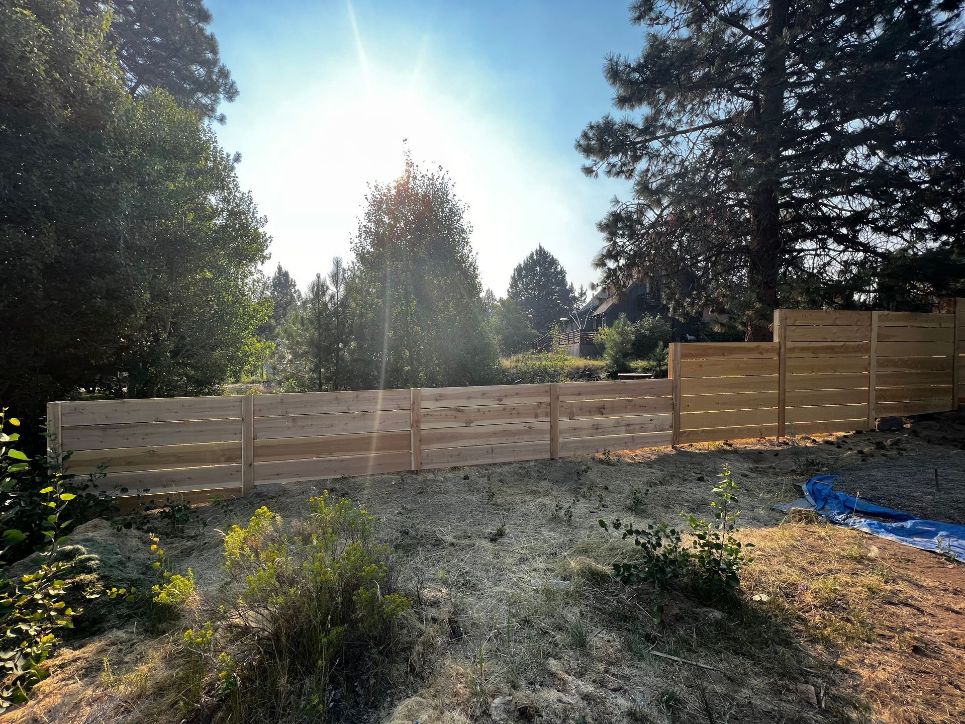 A wooden fence is surrounded by trees on a sunny day.