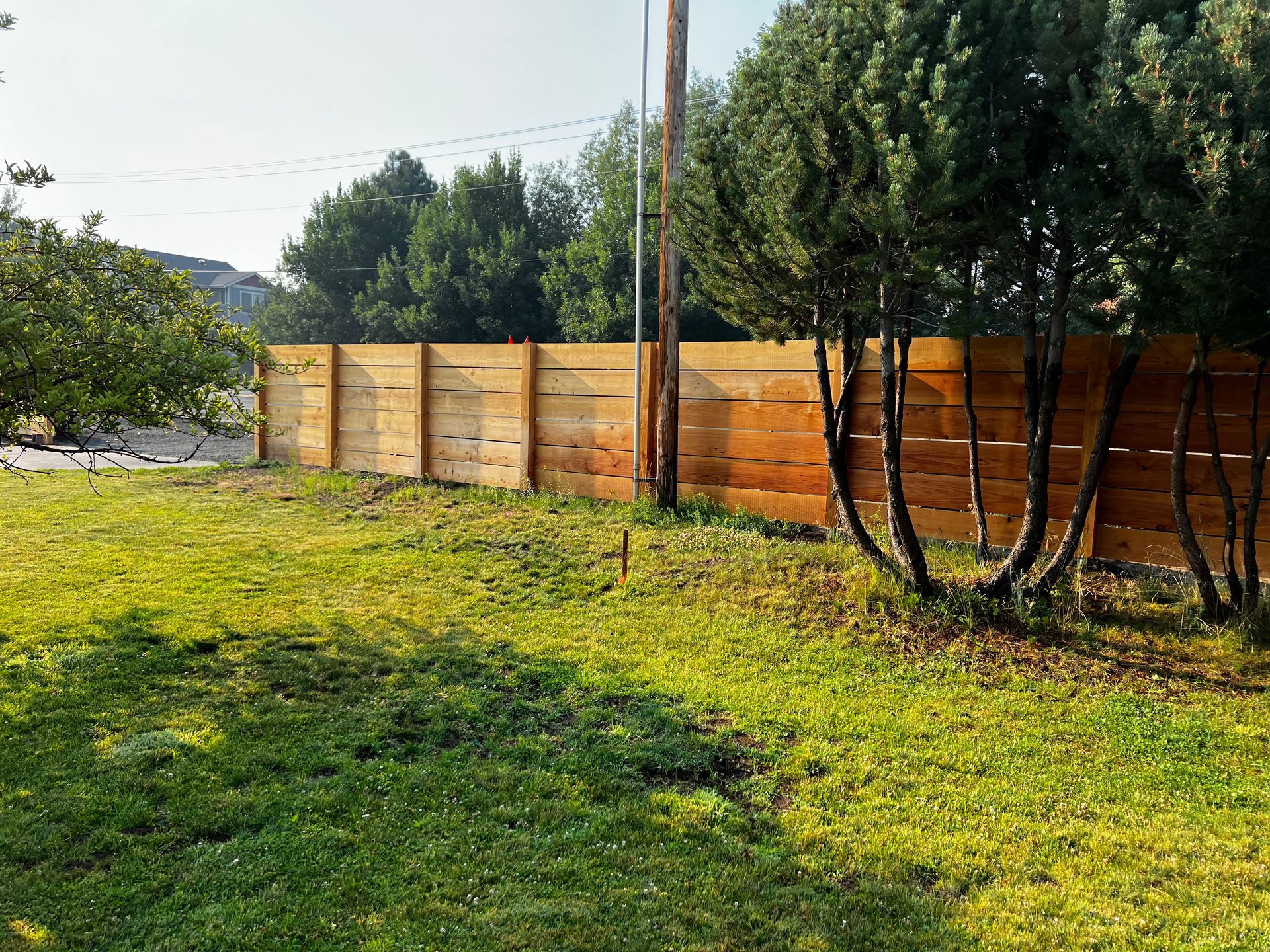 A wooden fence surrounds a lush green field.