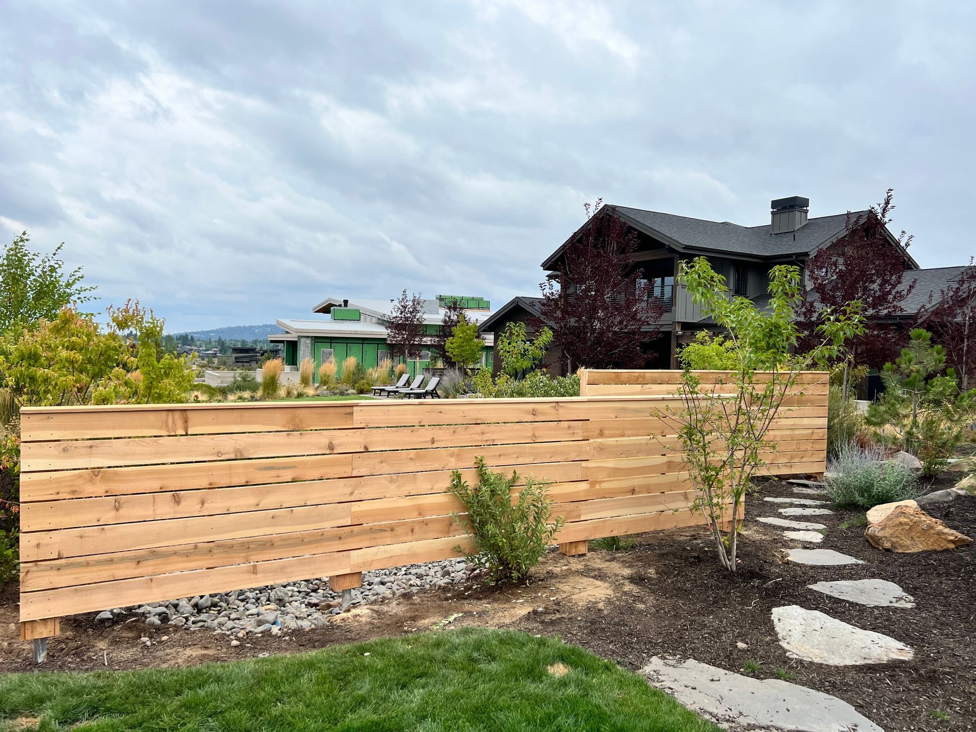 A wooden fence in a backyard with a house in the background.