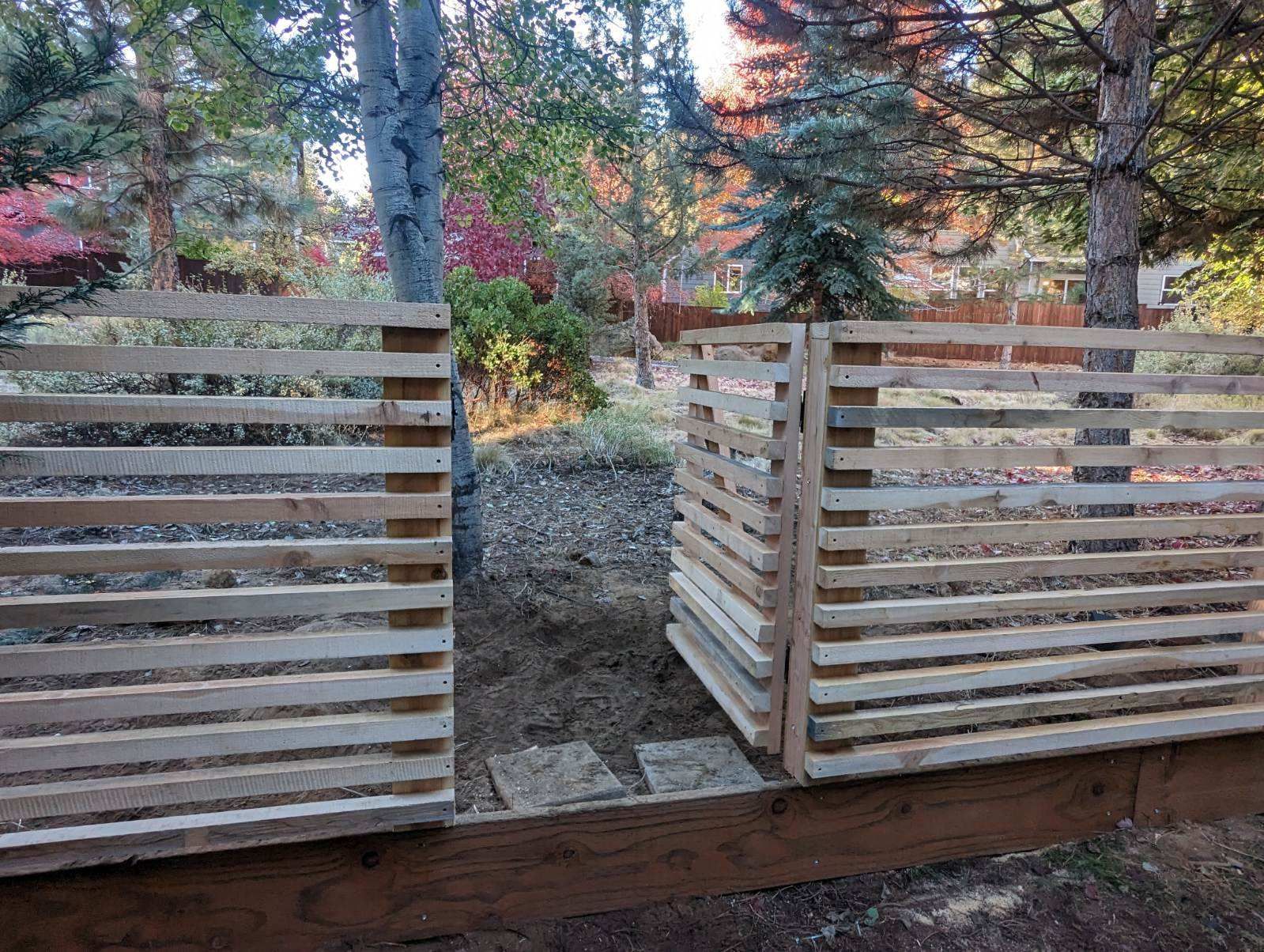 A wooden fence is sitting in the middle of a forest.