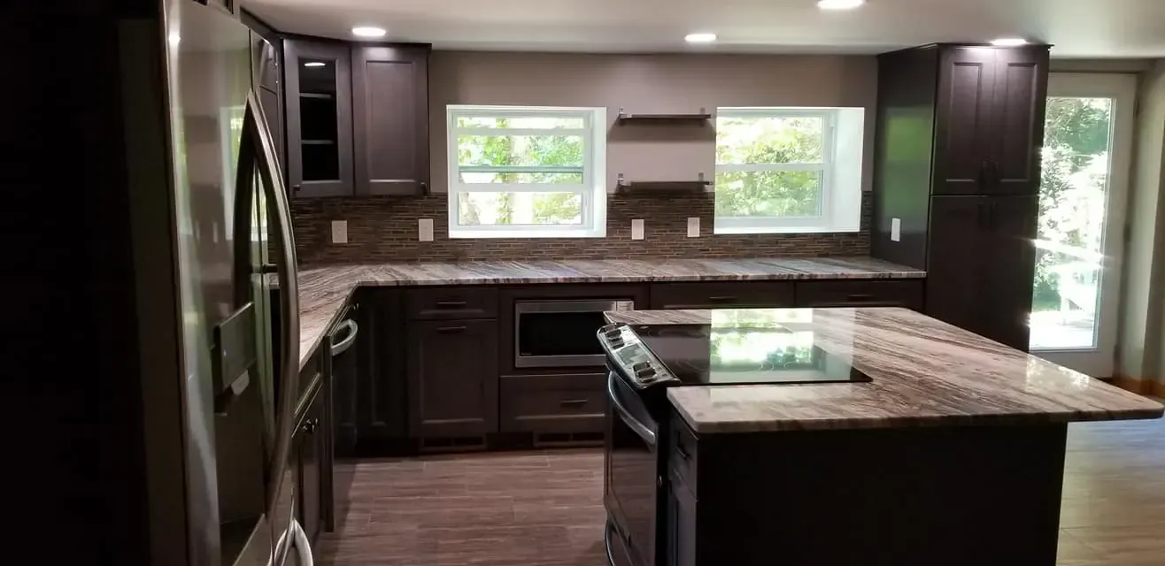 Modern kitchen with dark brown cabinets, granite countertops, and a central island.