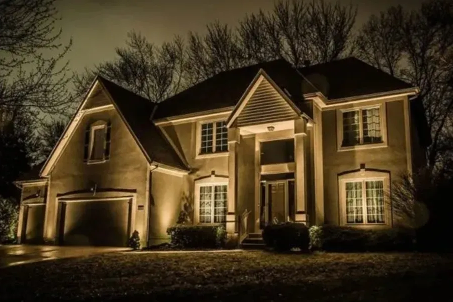 Image of a home at night with a soft golden uplighting on it.