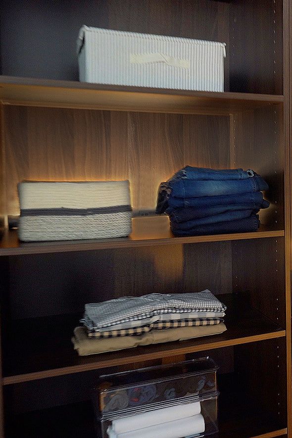 Wooden shelves holding folded clothes and storage boxes.