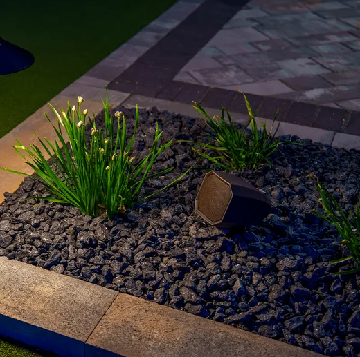 Image of an AMP Symphony outdoor audio speaker in someone's backyard at night.