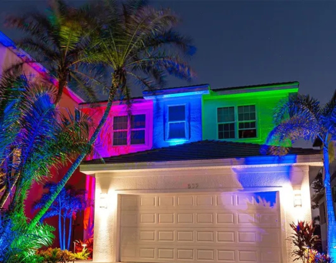Image of an exterior of a Florida home with rainbow uplighting on it.