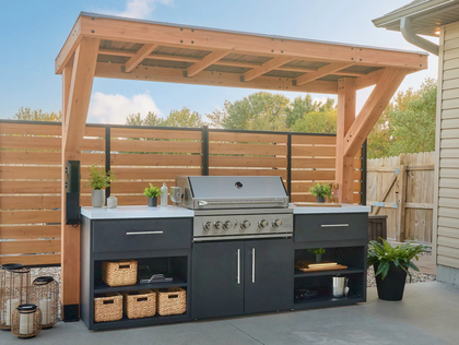 Outdoor kitchen with grill, cabinetry, and wooden pergola.