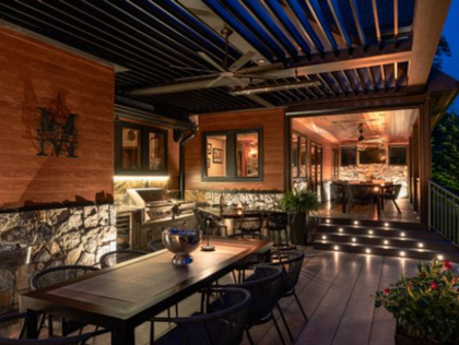 Outdoor patio with dining area, grill, and retractable roof. Warm lighting, stone and wood accents.