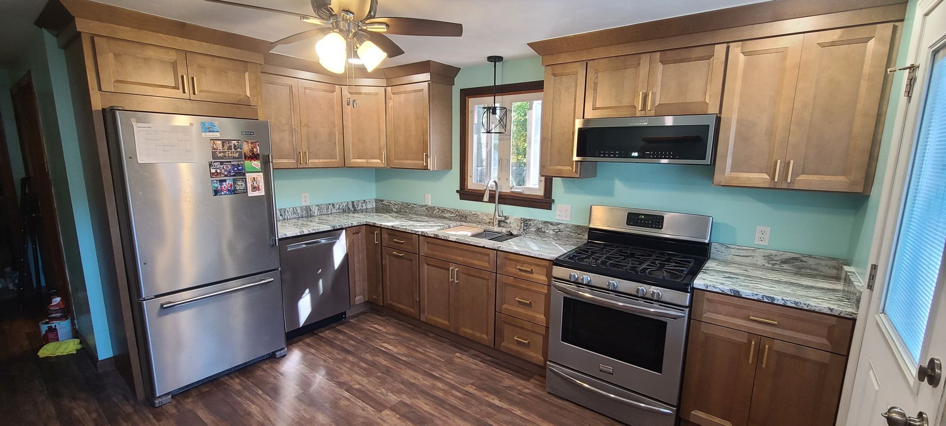 Image of a homeowner's kitchen after a renovation. Light brown cabinets and light gray countertops with a light blue wall.