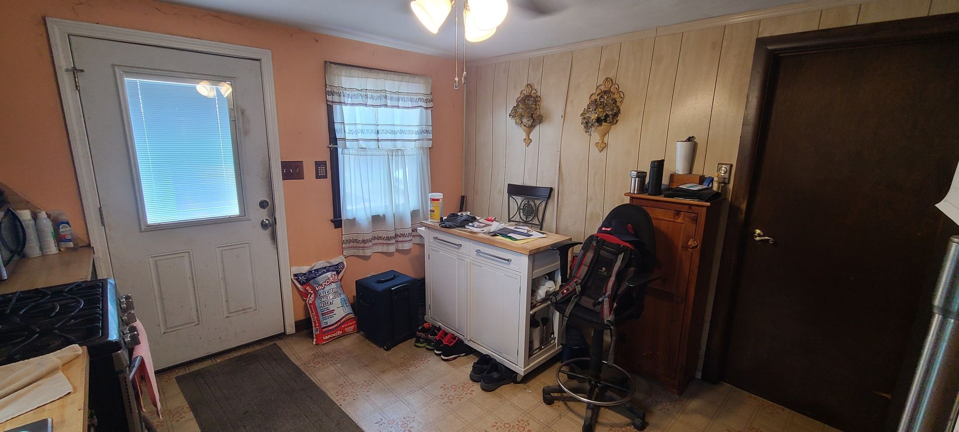Image of a homeowner's kitchen before a renovation. Orange and light tan walls and random objects scattered around.