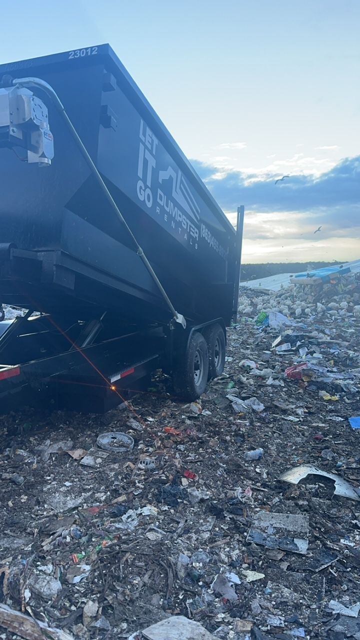 A dumpster is sitting in the middle of a pile of trash.