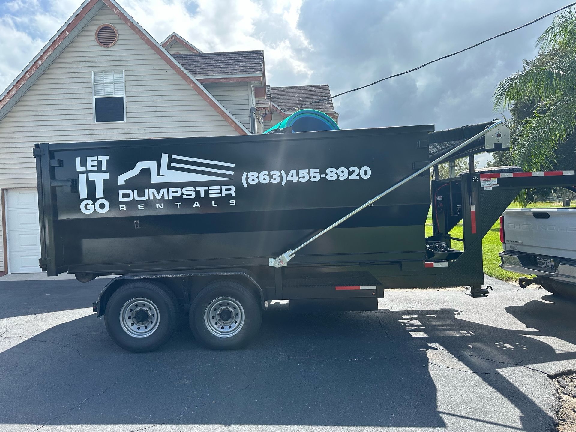 A dumpster trailer is parked in front of a house.