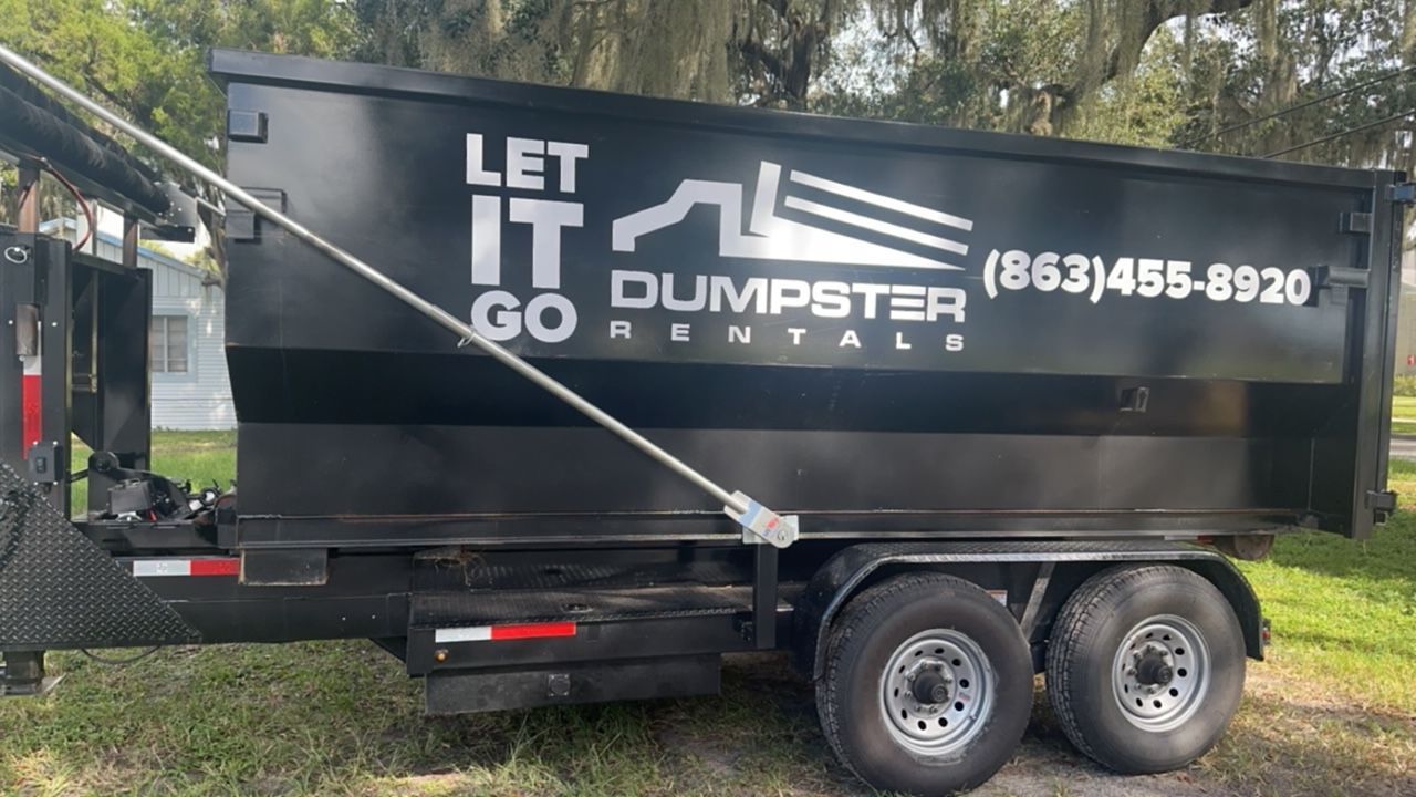 A black dumpster is parked on the side of the road.