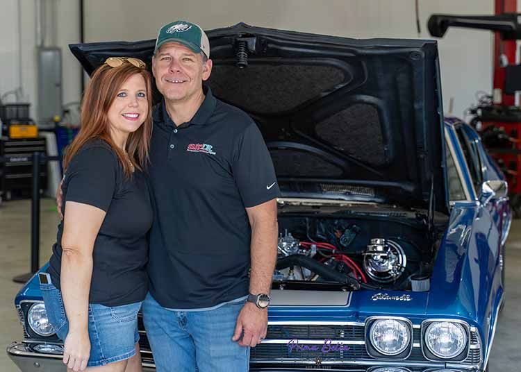 The owners of Auto DR stand in front of a vintage car from Macomb County.