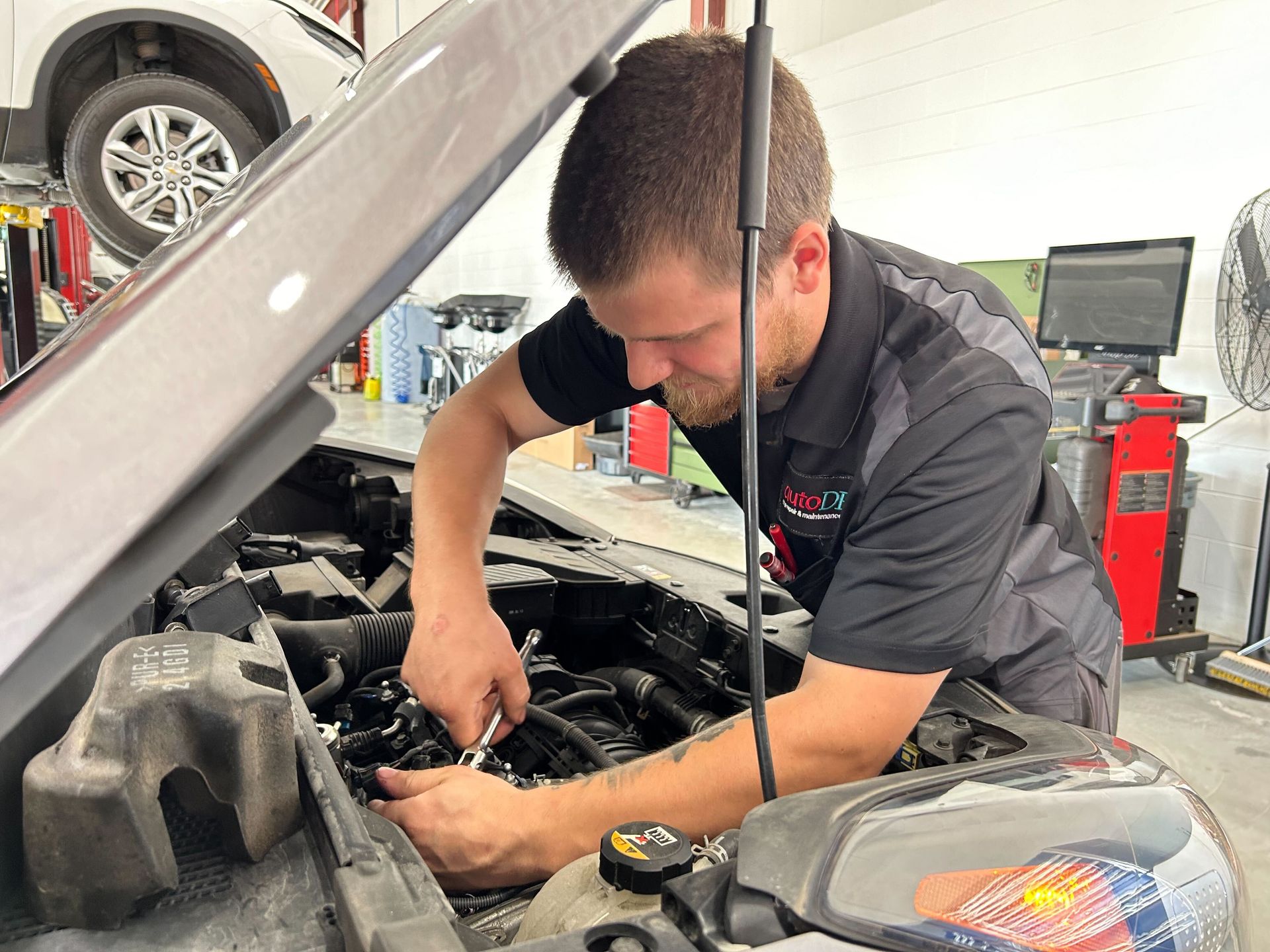 A mechanic using a wrench to work on a car's engine from a customer that lives in Port Huron. 