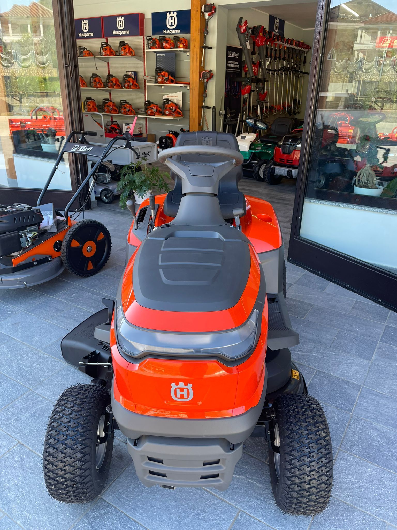 Un trattorino rasaerba arancione esposto all'esterno di un negozio di attrezzature per esterni.