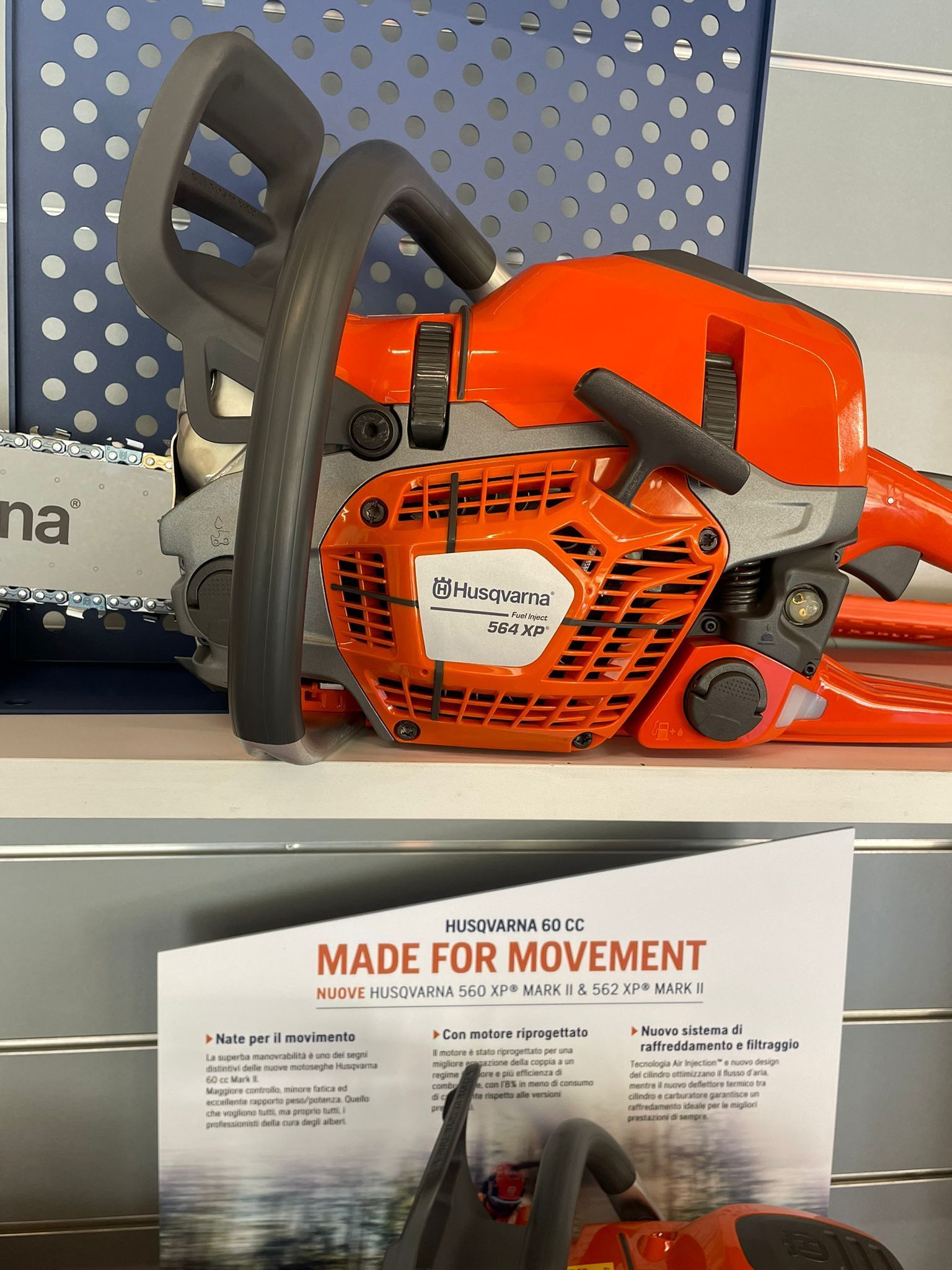 Una motosega arancione esposta in un negozio, con alle spalle l'insegna 