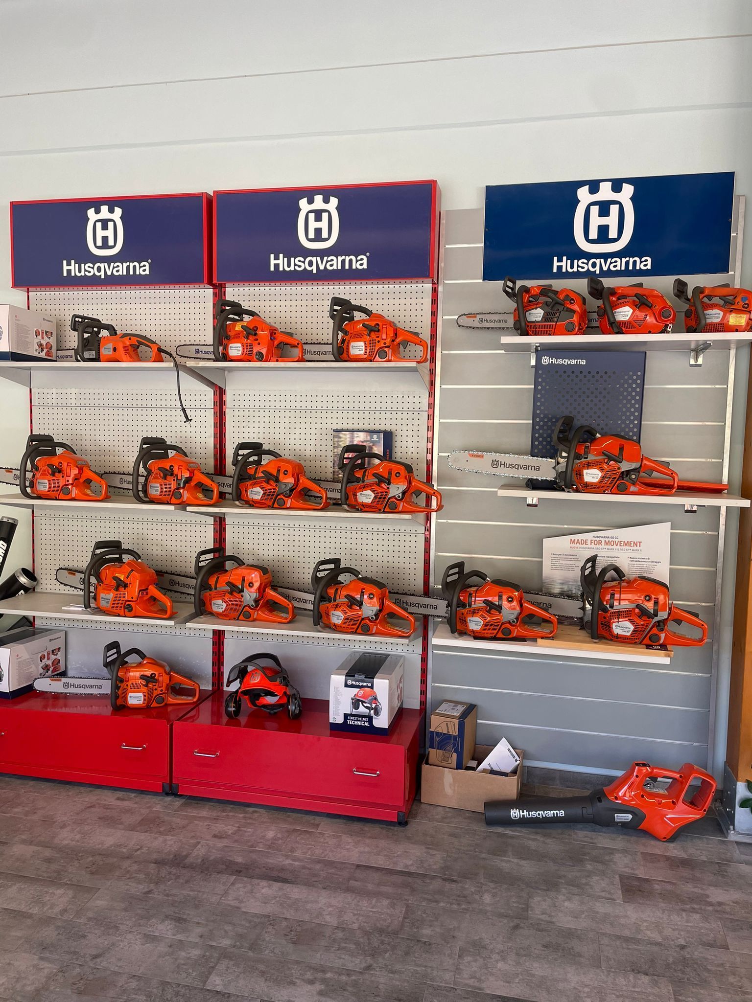 Motoseghe esposte su scaffali rossi e grigi, con il logo Husqvarna sopra di esse.