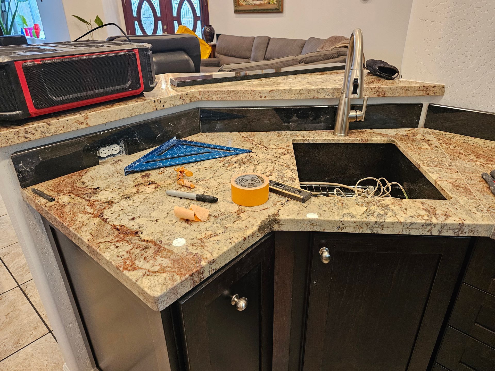 Partially built kitchen counter with granite top, sink cutout, tools, and construction dust
