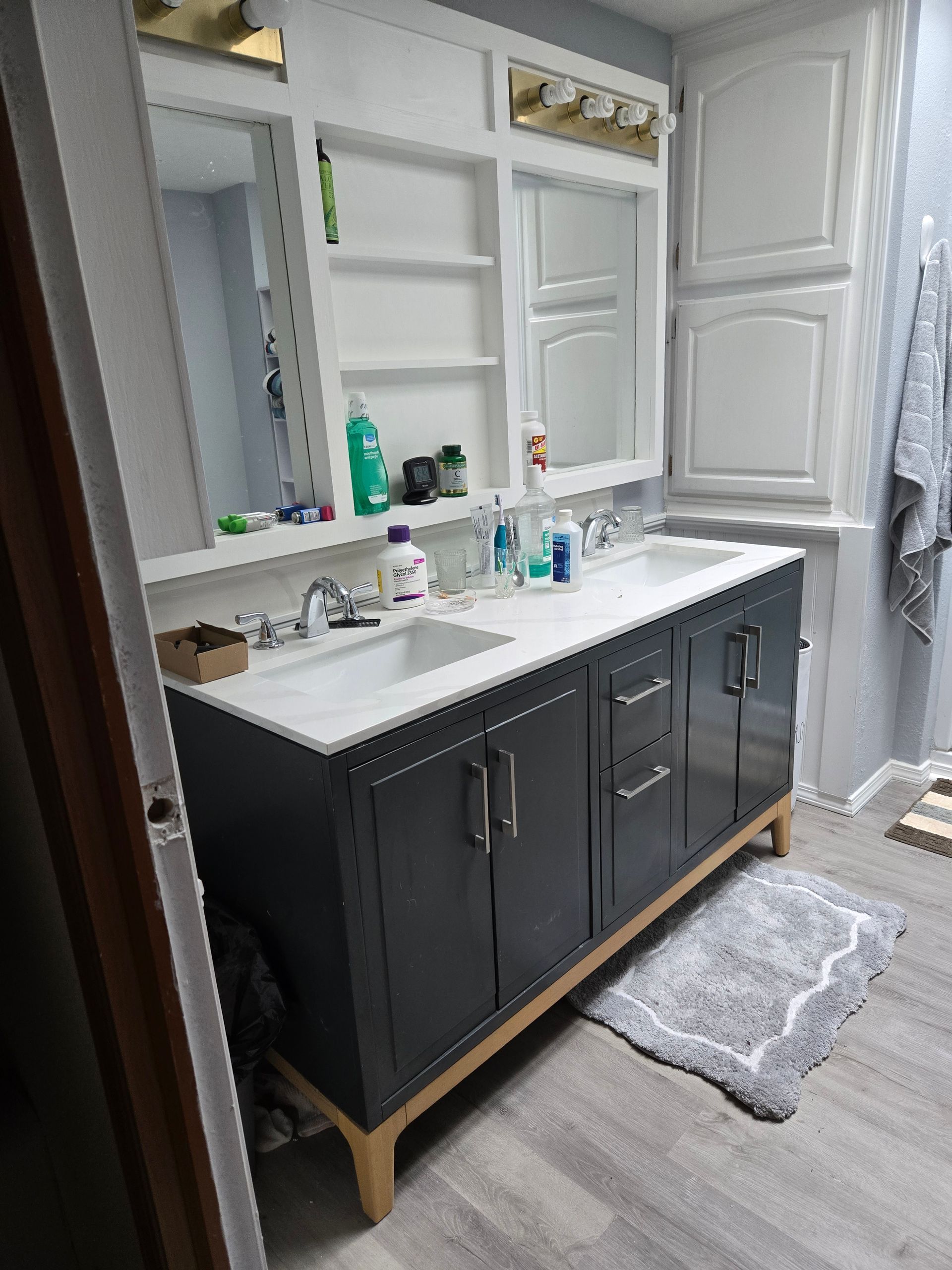 Bathroom vanity with double sinks, black cabinets, white countertops, and mirrors above