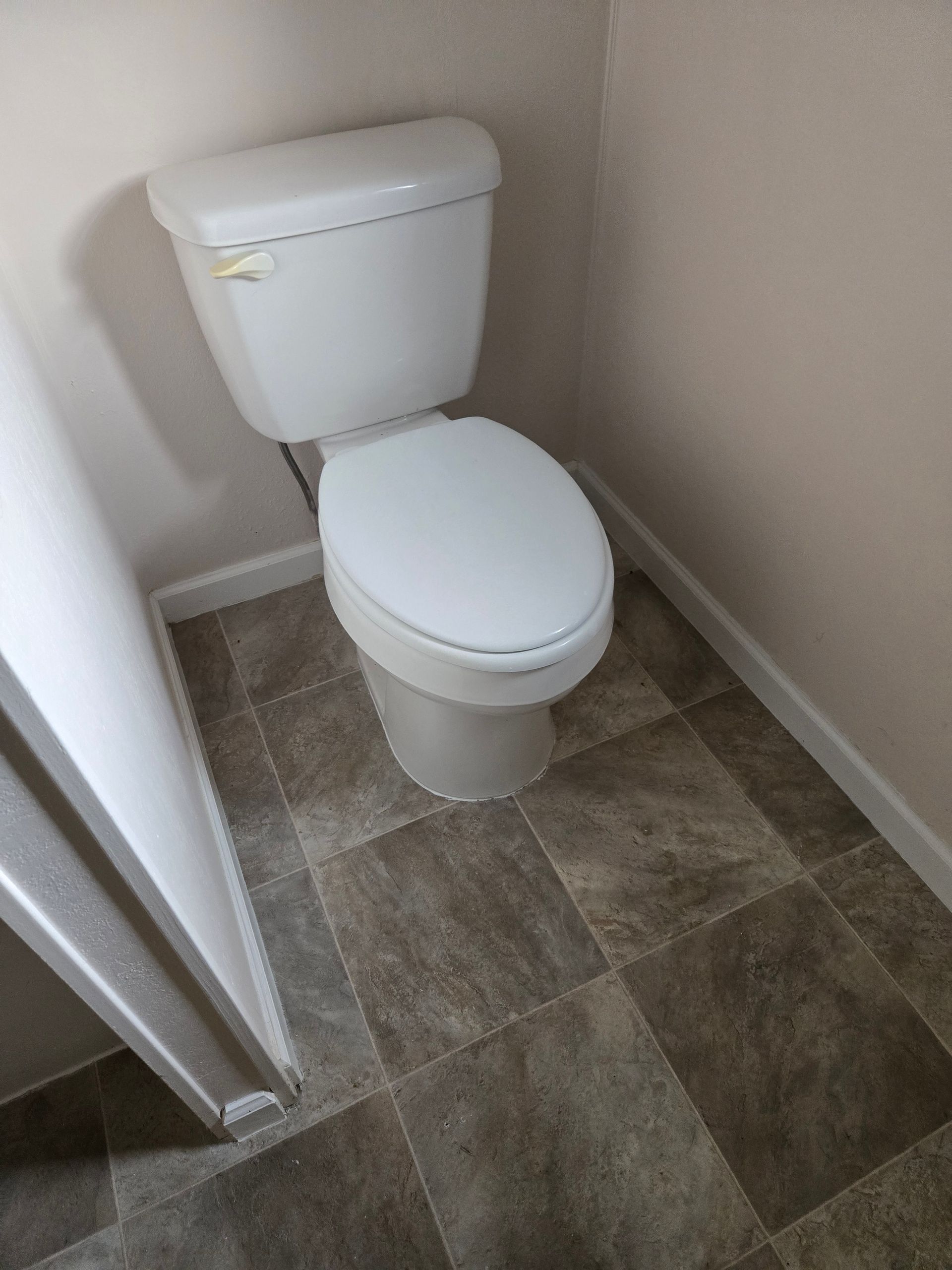 Small bathroom with a white toilet on gray tile flooring.