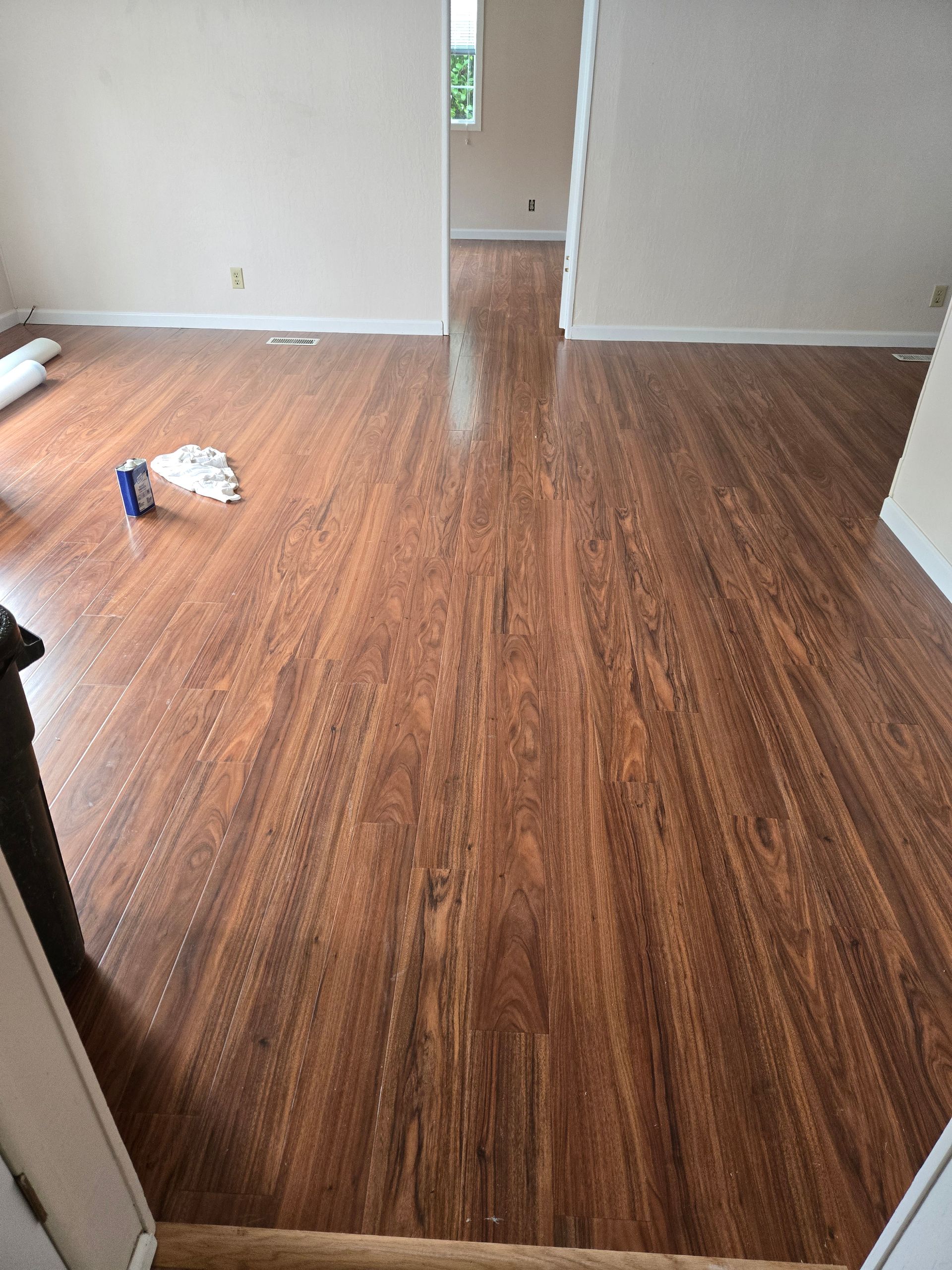 Empty room with brown wood flooring, white walls, and a doorway at the back.