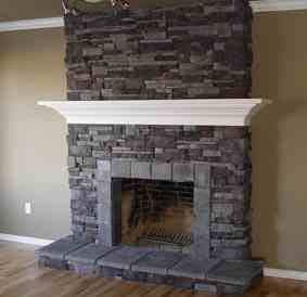 Stone fireplace with dark stacked-stone surround, white mantel, and raised hearth in a beige room